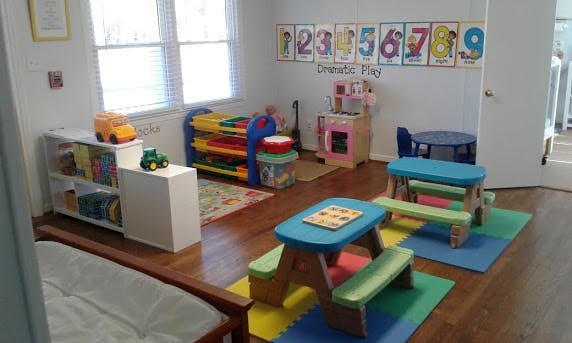 Playroom with small tables and chairs, toy kitchen, and shelves with toys