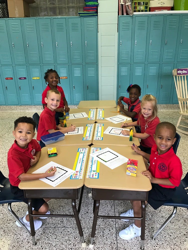 Six children sitting at desks in a classroom