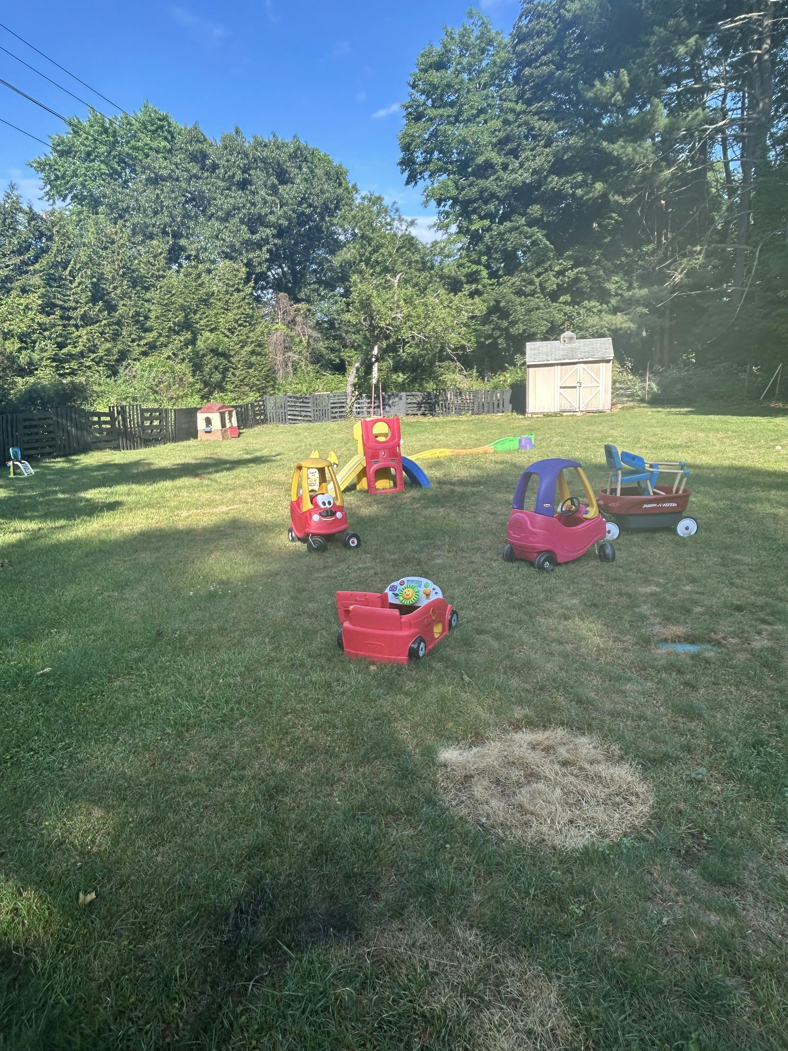 A backyard with children's toys and a small shed