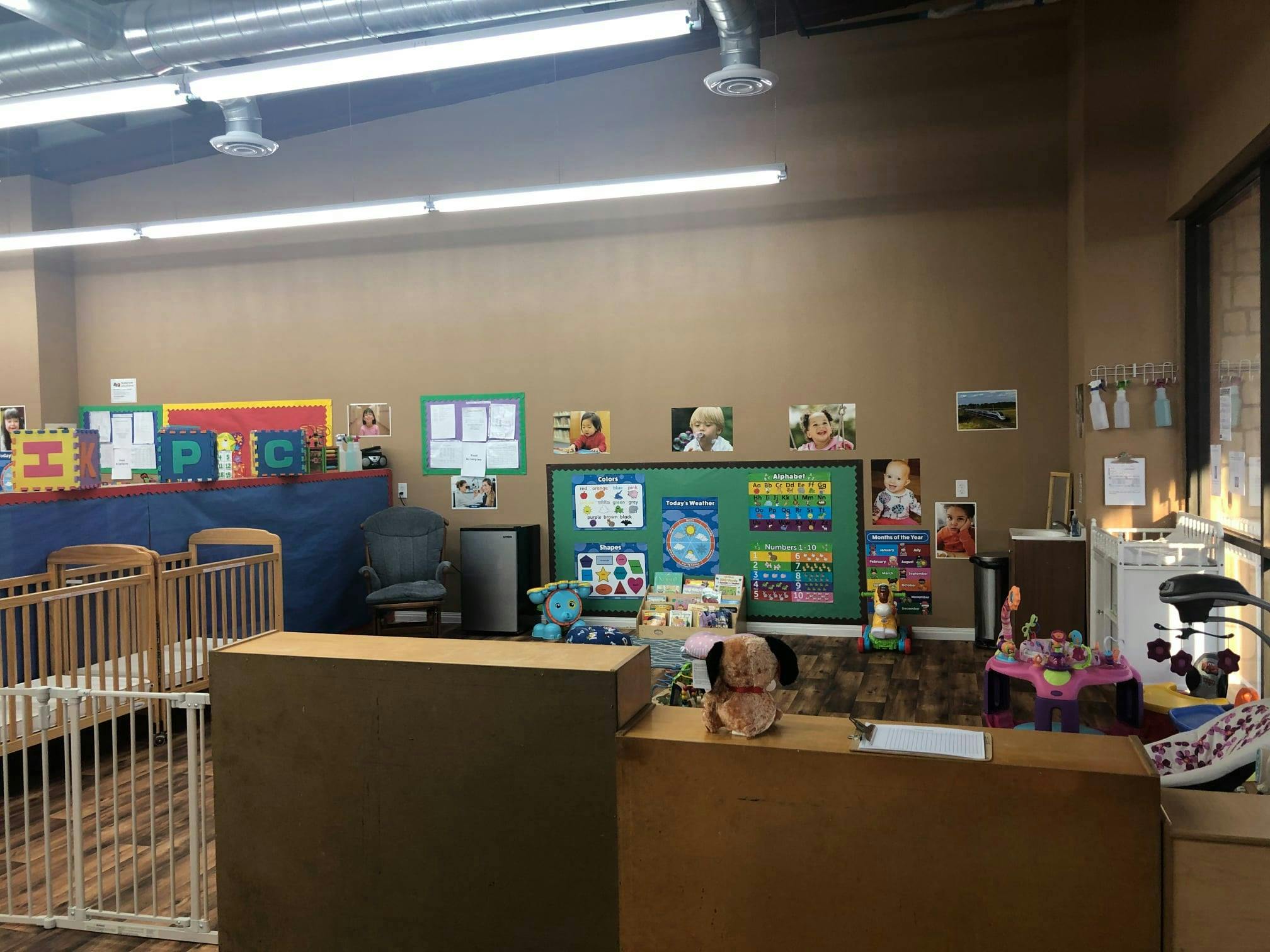 Daycare room with cribs, play area, and bulletin boards