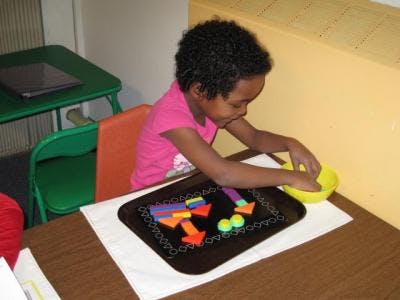 Child playing with colorful shapes on a tray