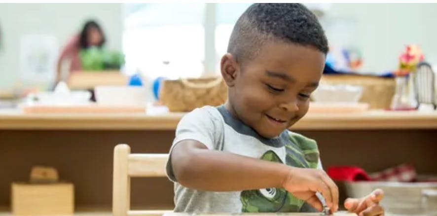 Child at a table working with hands