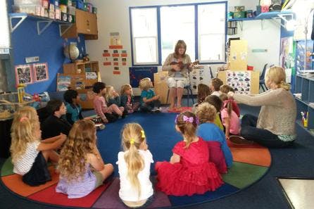 Adults and children sitting in a circle in a classroom