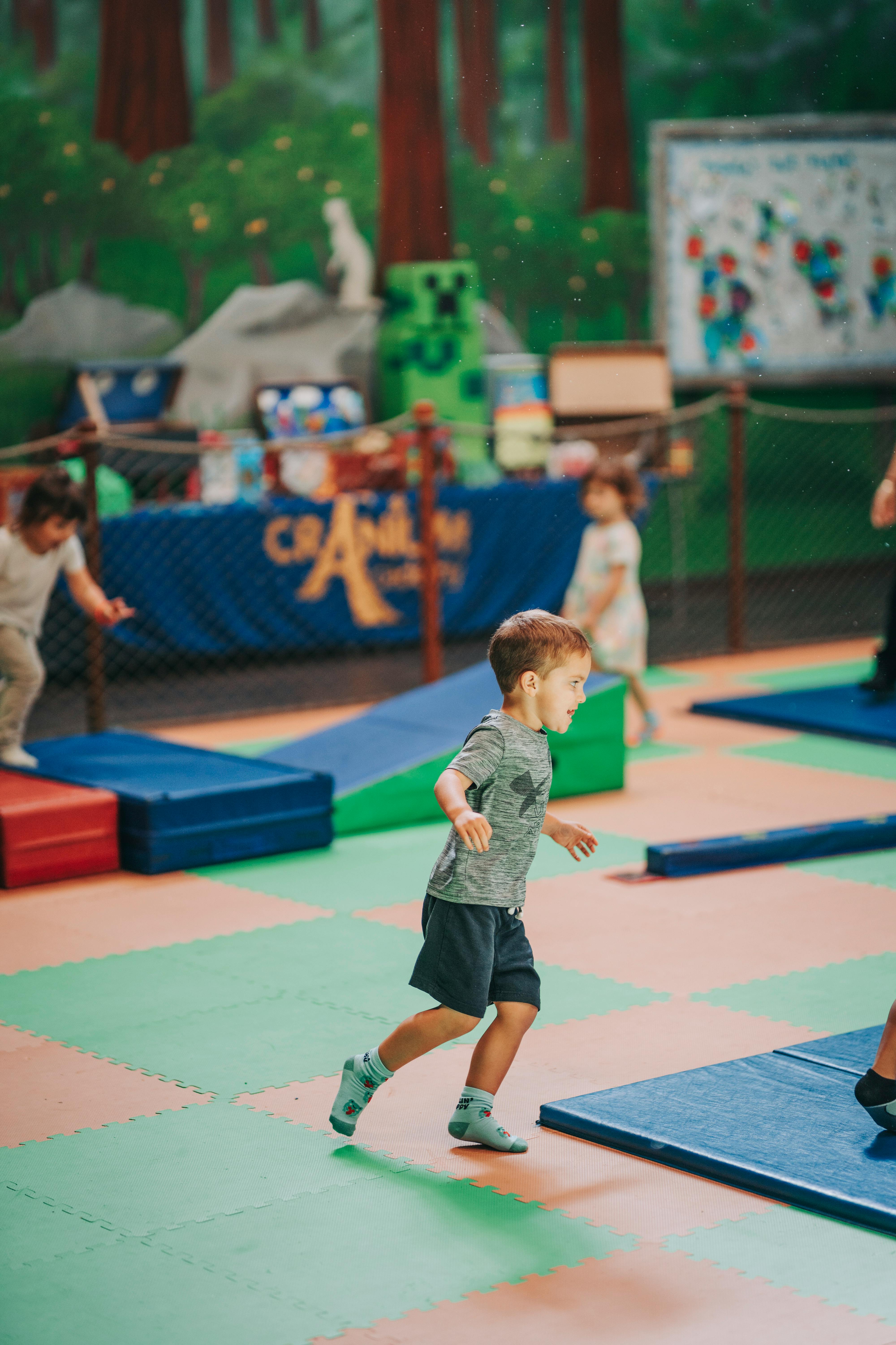 Child running on a colorful mat in an indoor play area