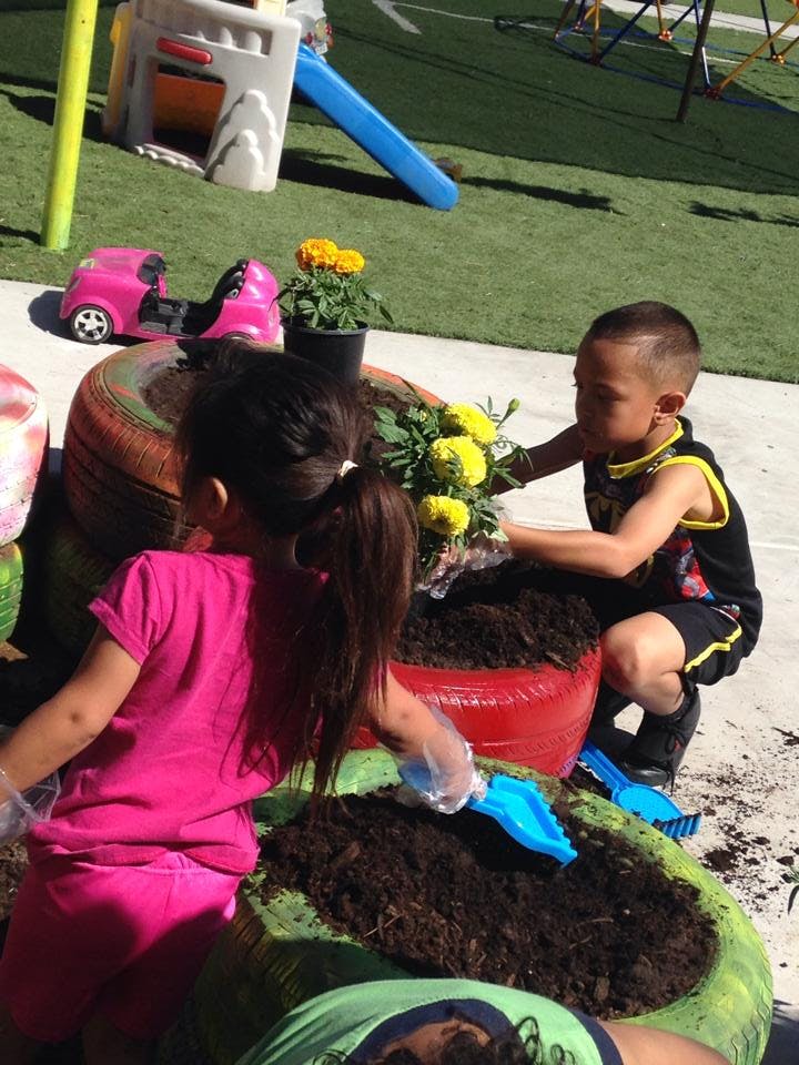 Two children planting flowers in large planters