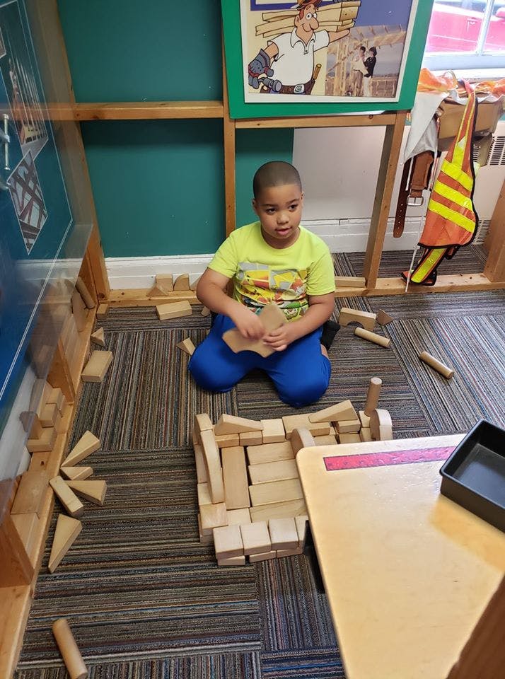 Child kneeling on floor playing with wooden blocks