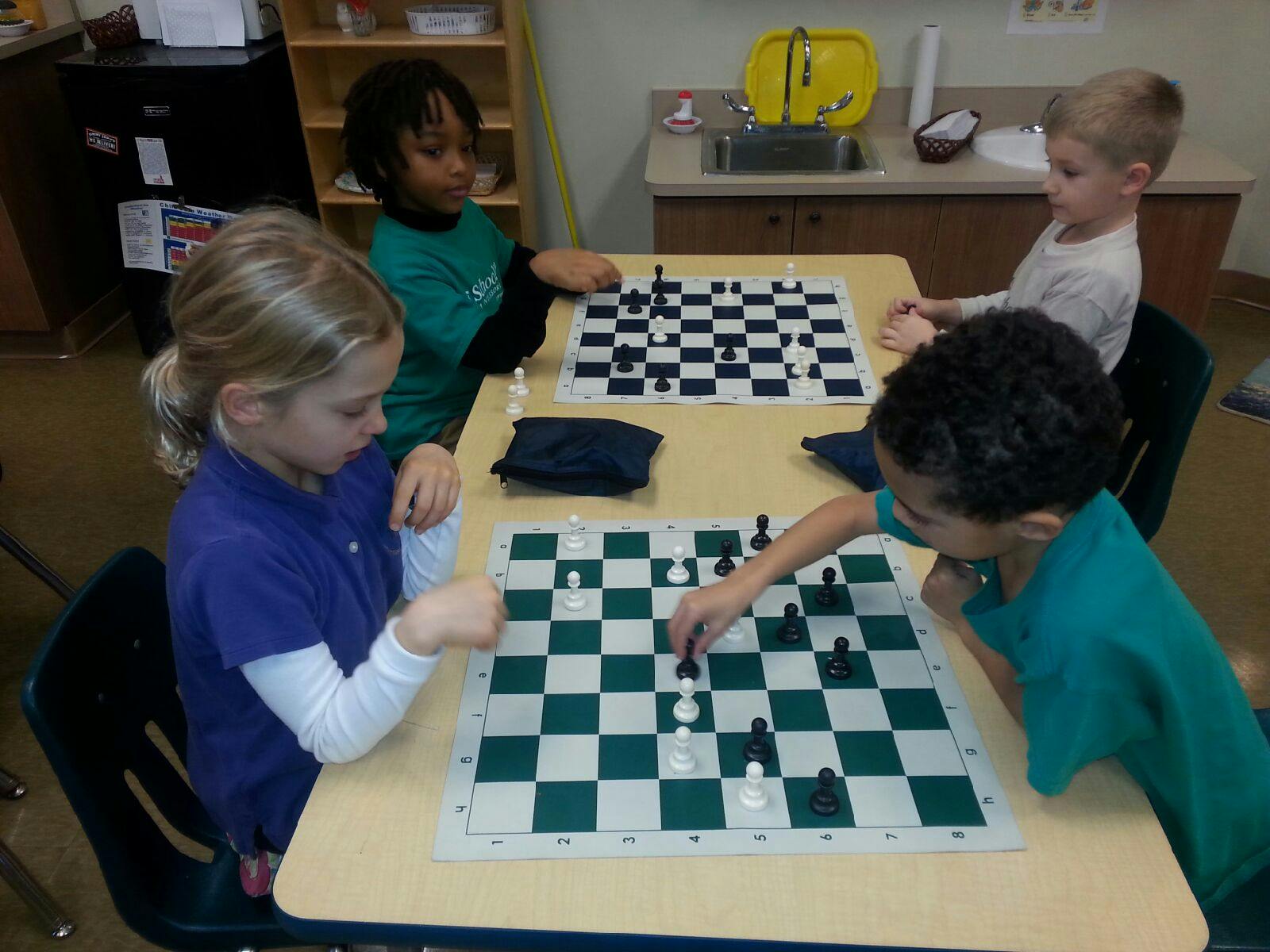 Four children playing chess at a table