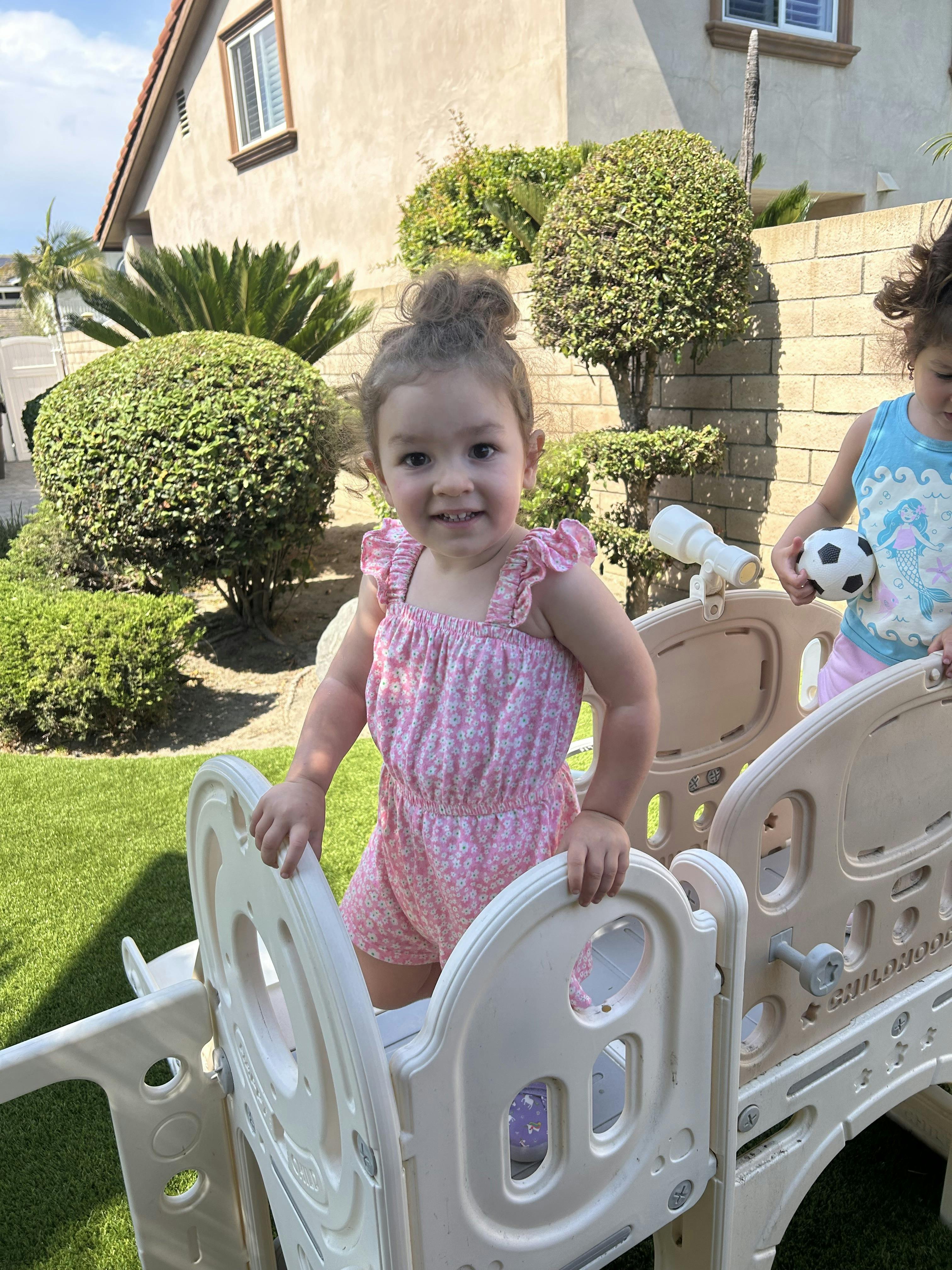 Child in pink outfit standing in a play structure