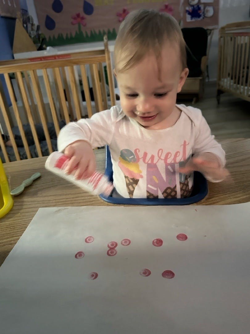 Child stamping red circles on white paper