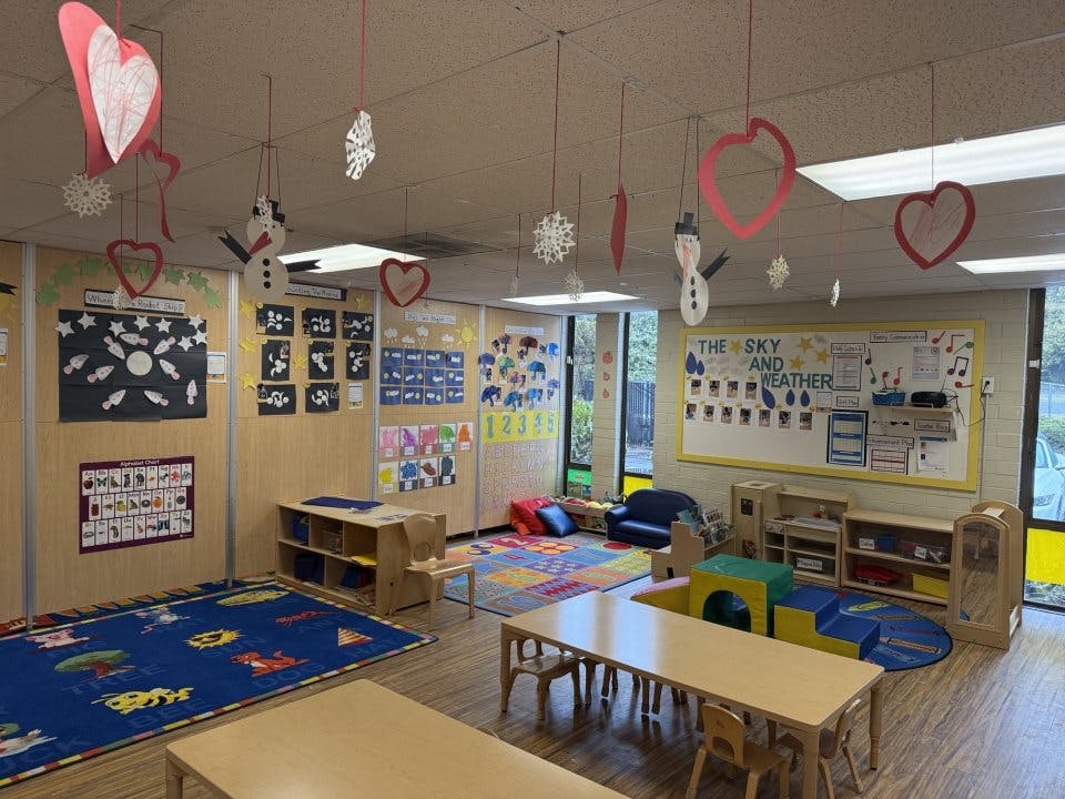 Classroom decorated with paper hearts, snowflakes, and snowmen hanging from the ceiling