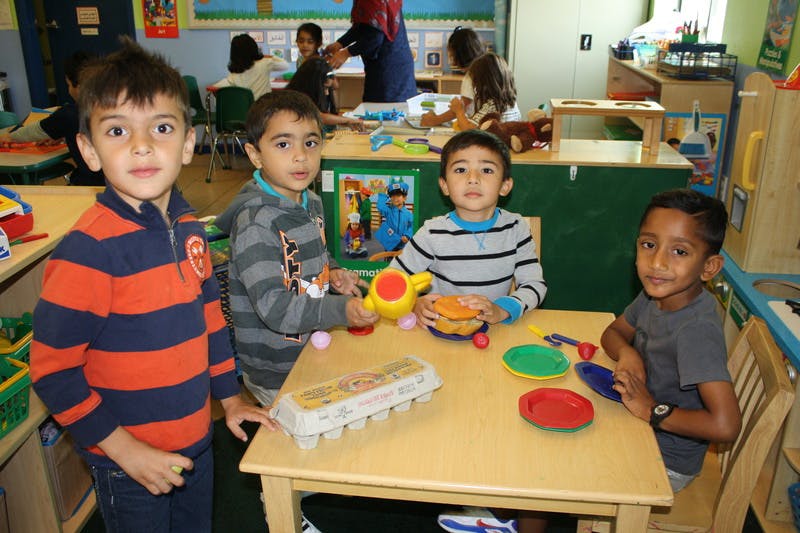 Four children playing with toys at a table in a classroom