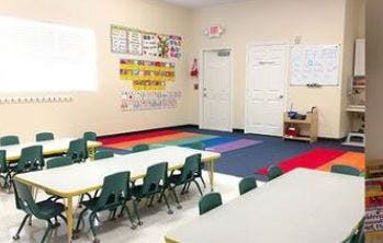 Classroom with small tables and chairs, colorful rug