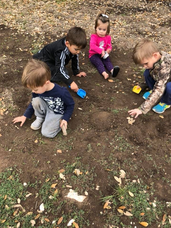 Four children playing in dirt with small shovels