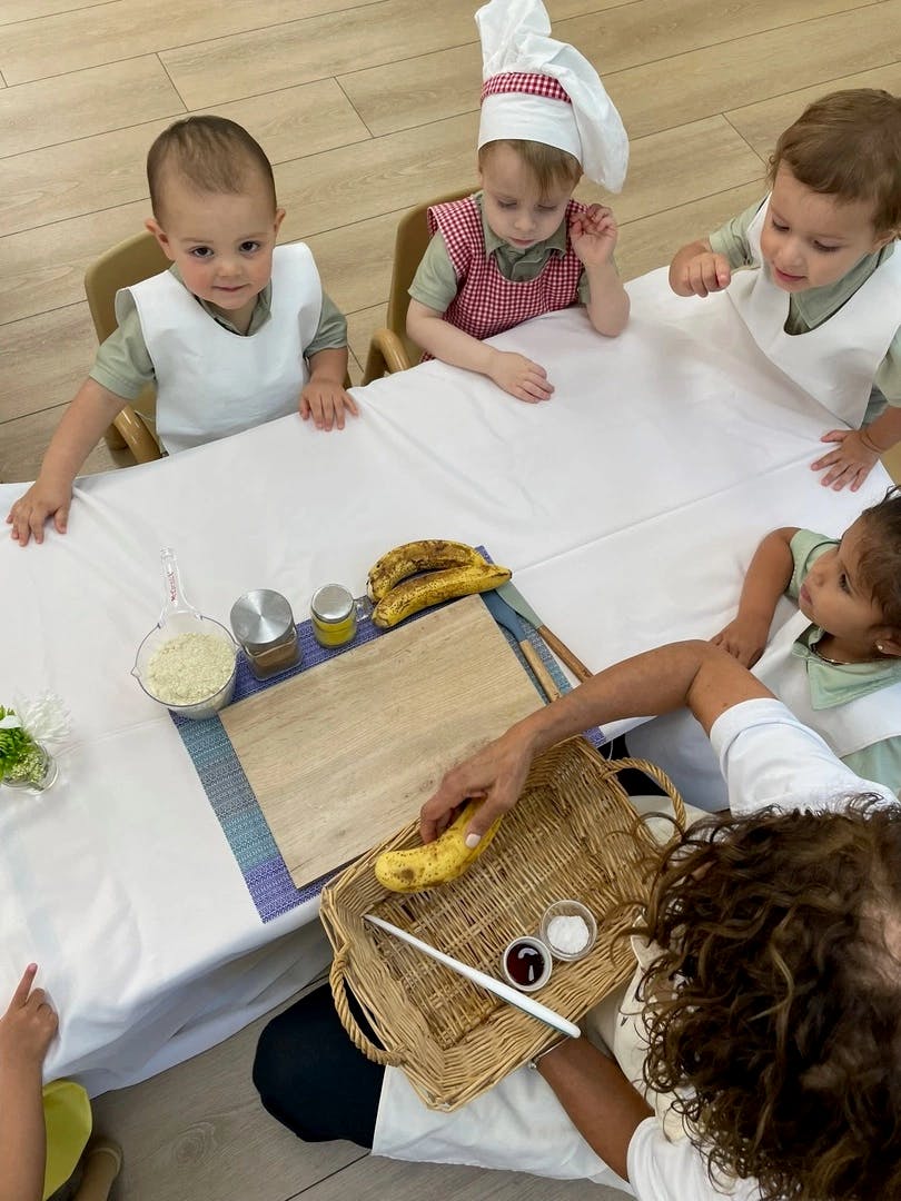Children at a table with an adult preparing food