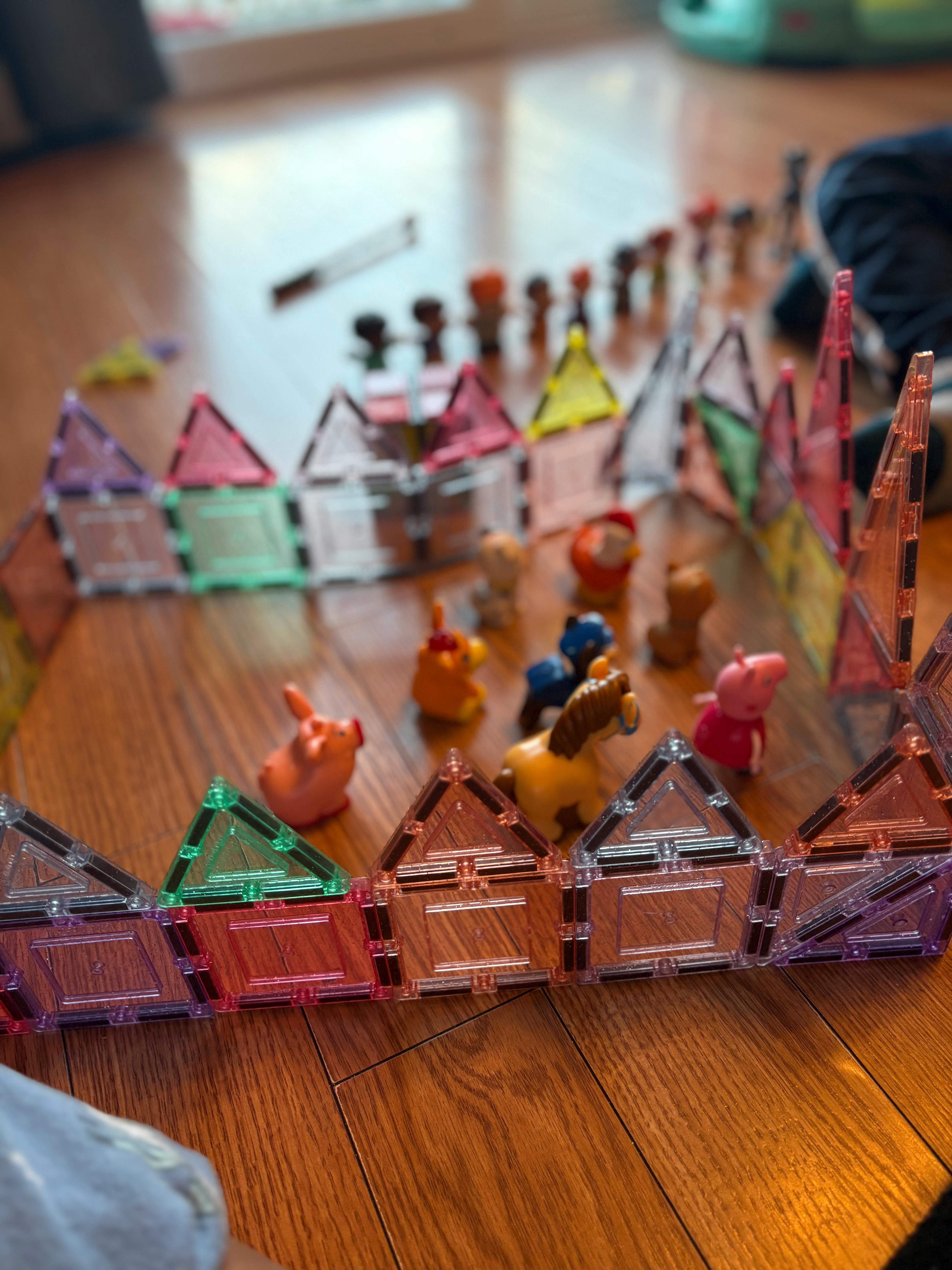 Magnetic tiles arranged into a structure with small animal toys inside