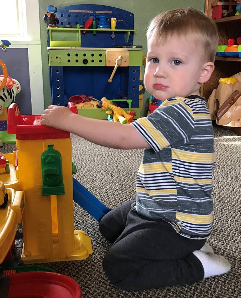 Child kneeling on carpet playing with a toy