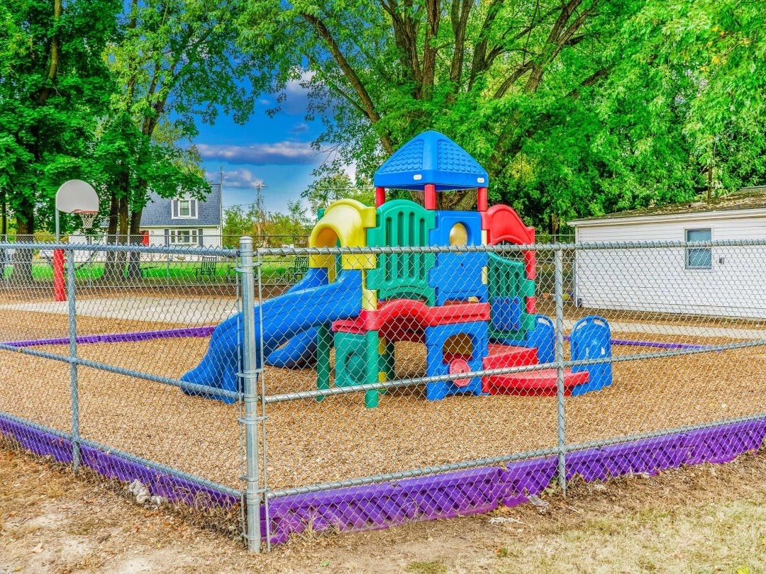 Colorful playground structure with slides and climbing areas behind a fence
