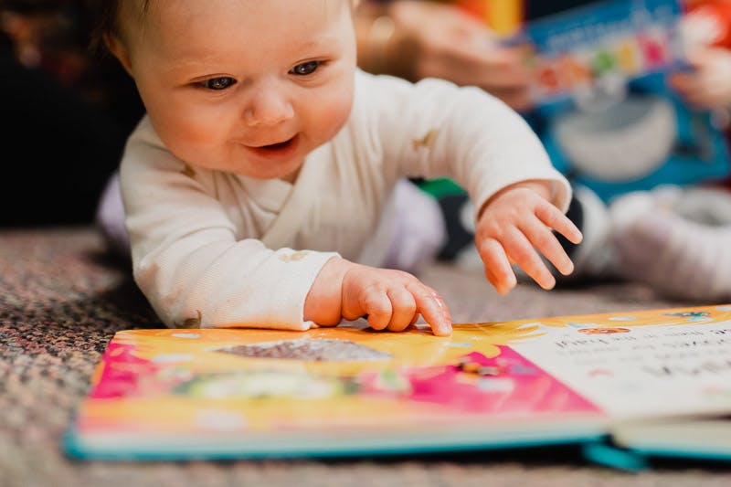 Child on stomach looking at an open book
