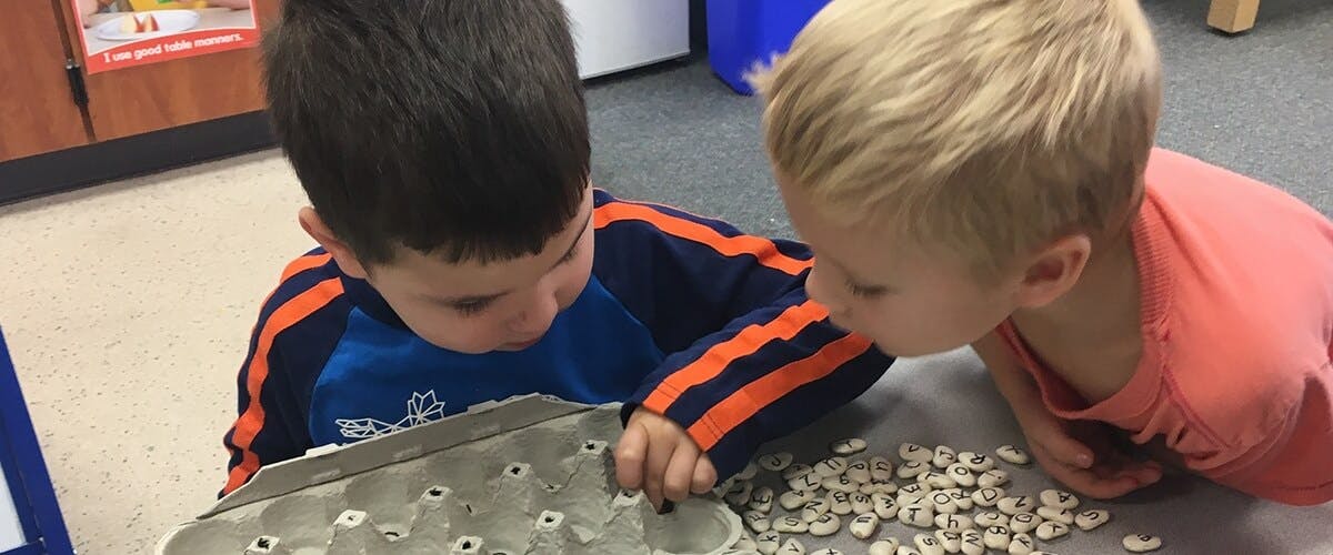 Two children looking at small objects on a surface