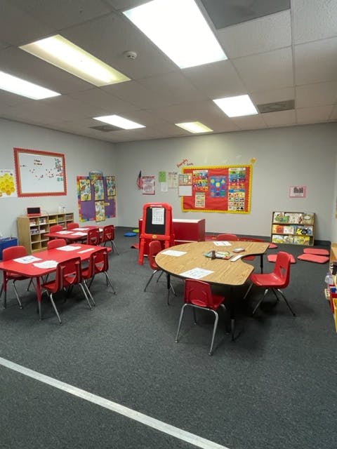 Empty classroom with small red tables and chairs