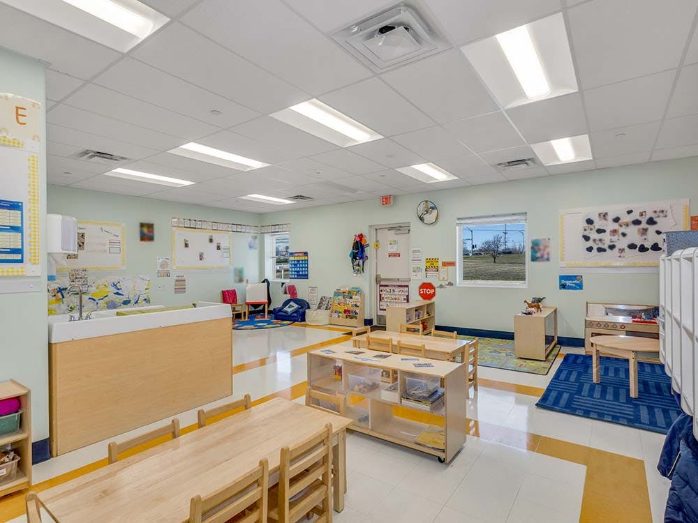 Empty classroom with small wooden tables and chairs