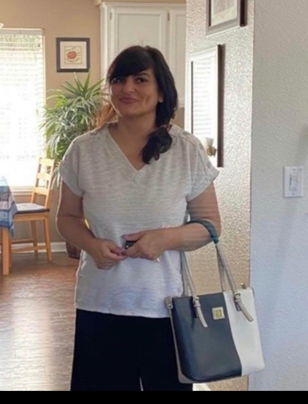 A person holding a handbag while standing indoors