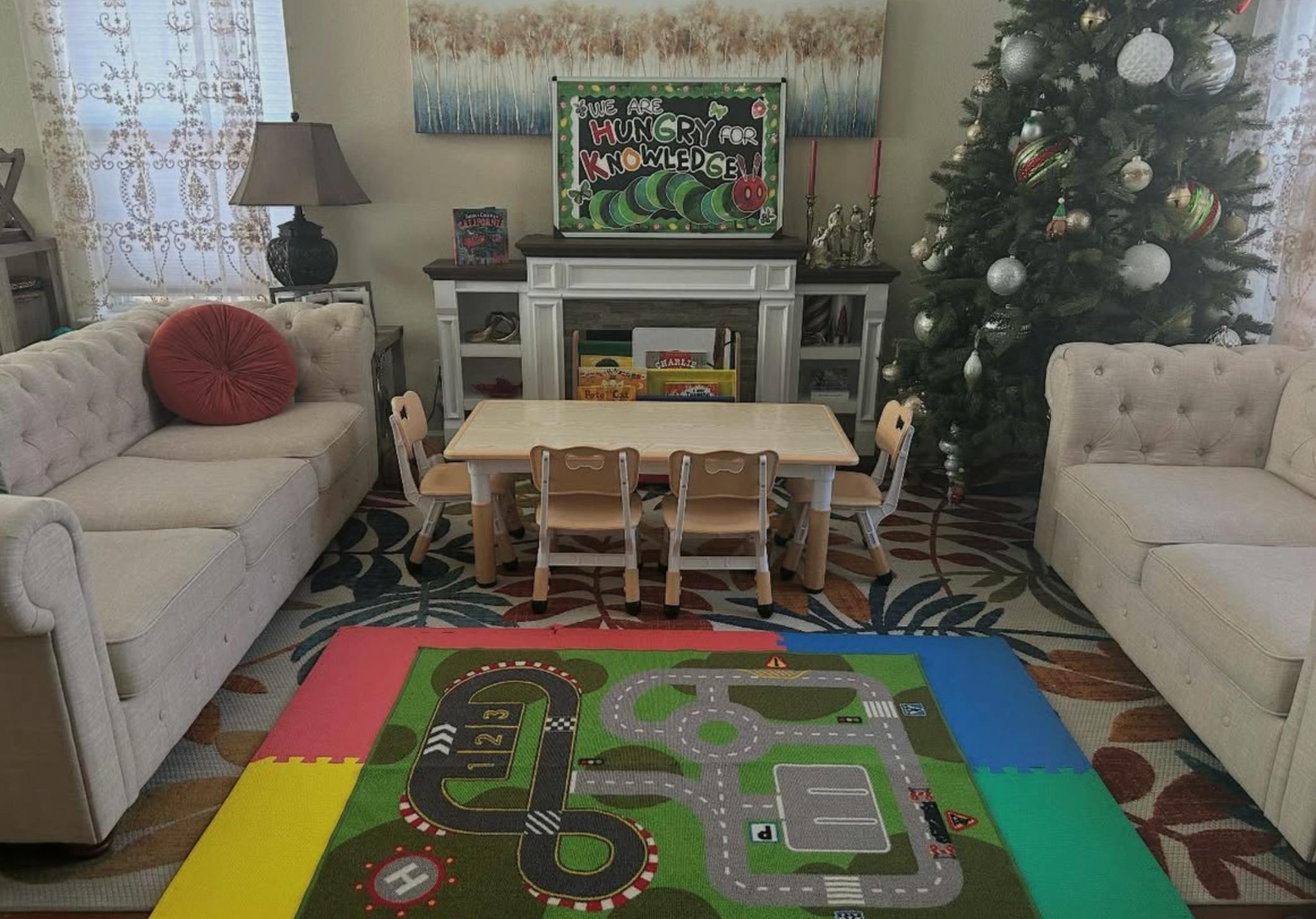 Living room with sofas, small table and chairs, Christmas tree, and playmat
