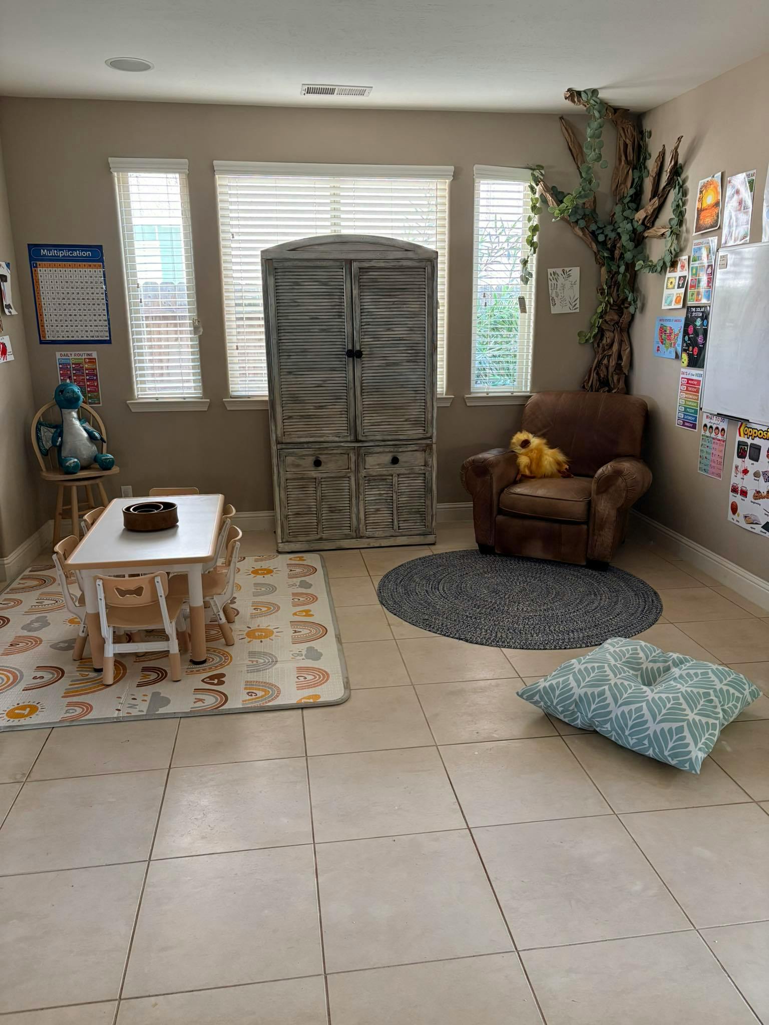 Children's play area with a small table and chairs, a stuffed dinosaur, and armchair