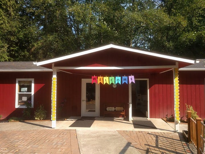 Red building with a white porch roof and a colorful "WELCOME" banner