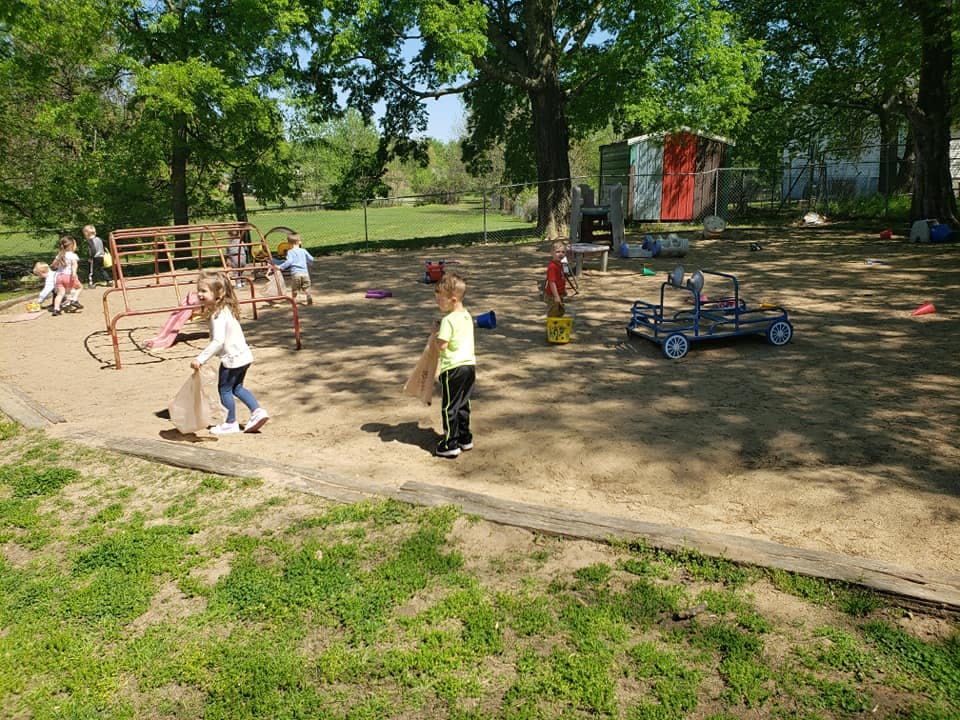 Children playing in a sandy area with playground equipment
