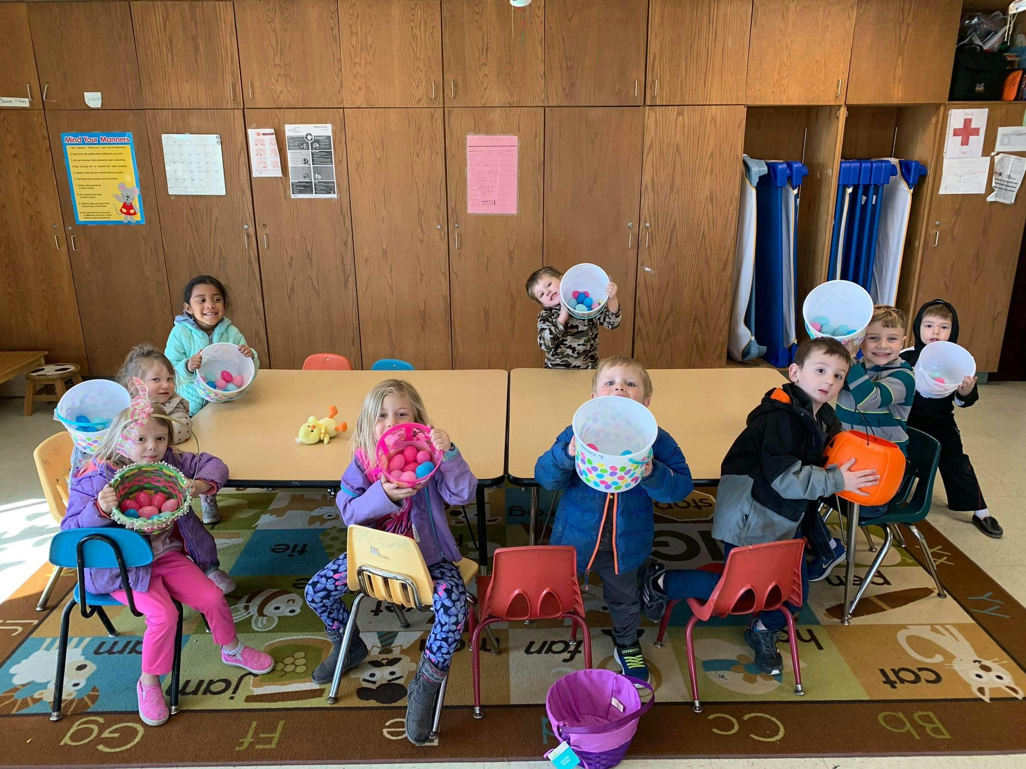 Children holding baskets and buckets in a classroom