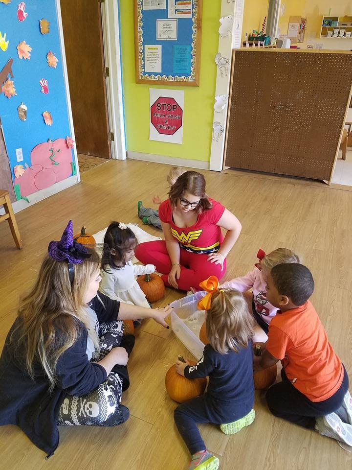 Person in Wonder Woman costume with children and pumpkins
