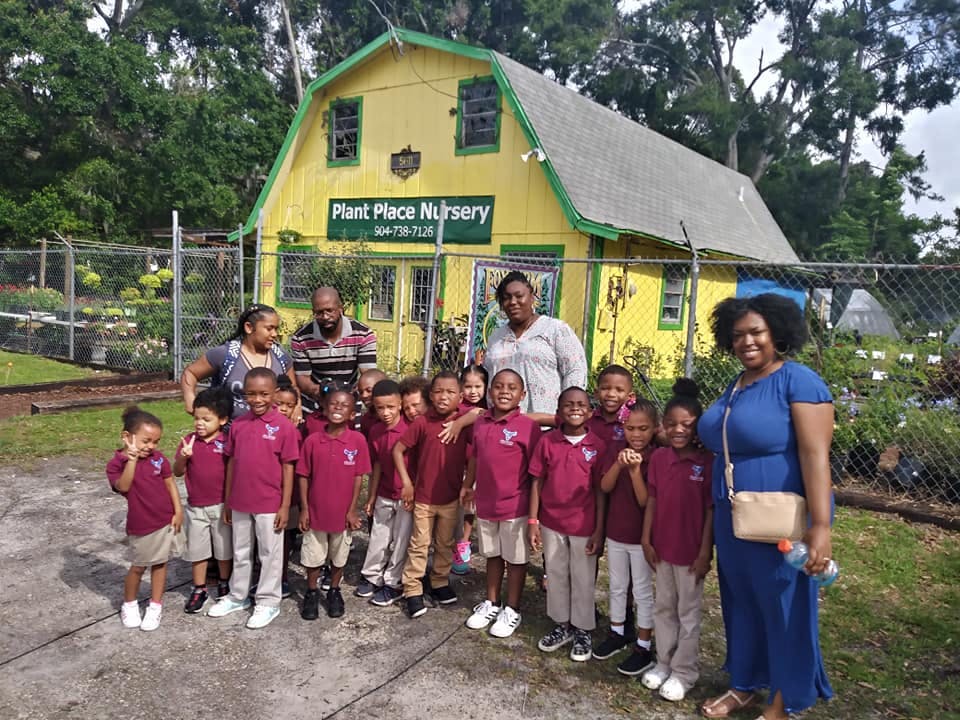 Adults and children in matching shirts standing in front of a building