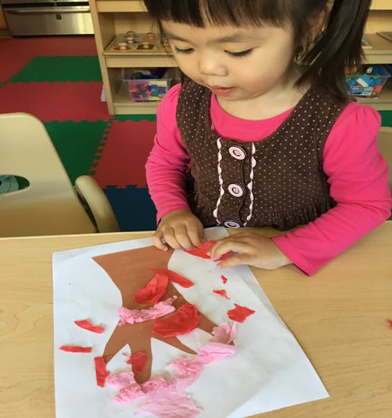 Child making a craft with paper cutouts on a table