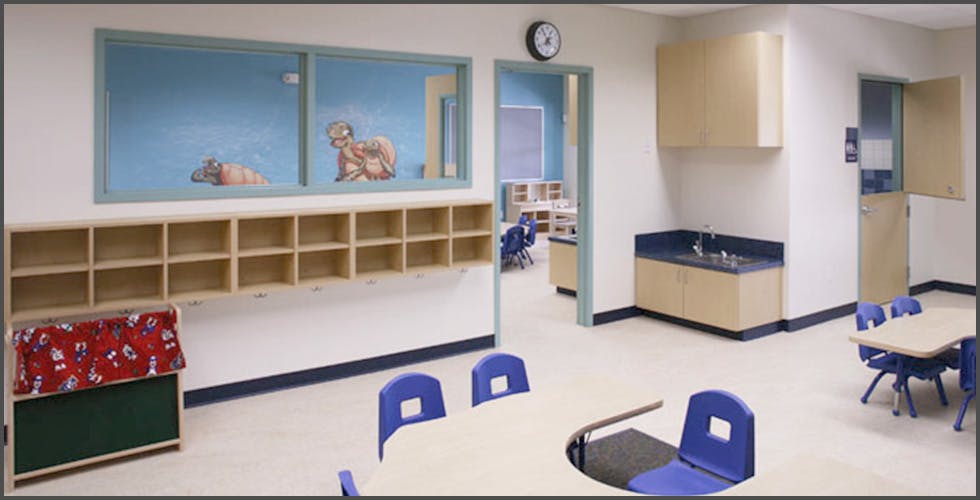 Classroom with cubbies, tables, chairs, and a sink area