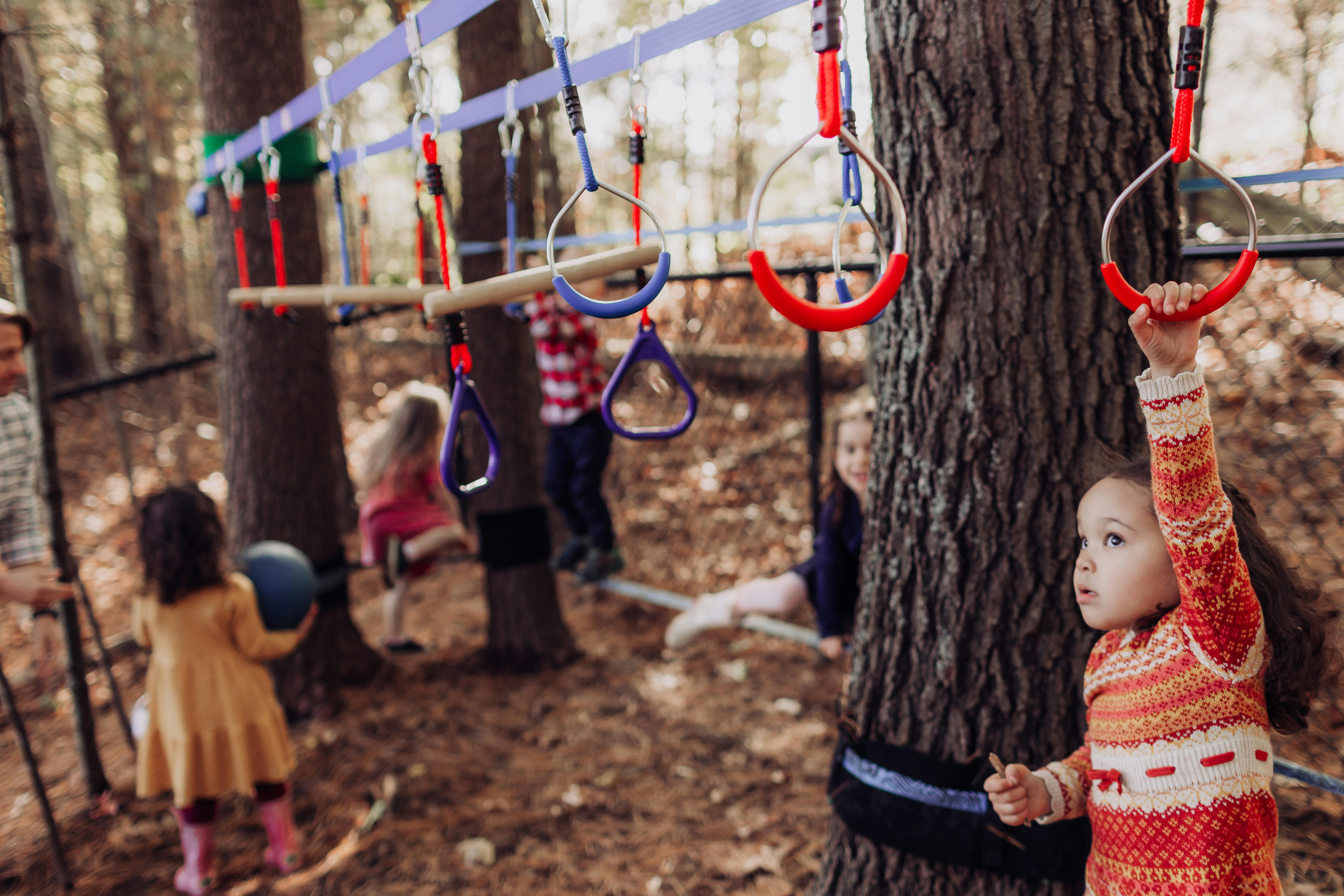 Child reaching for a red ring on an outdoor play structure