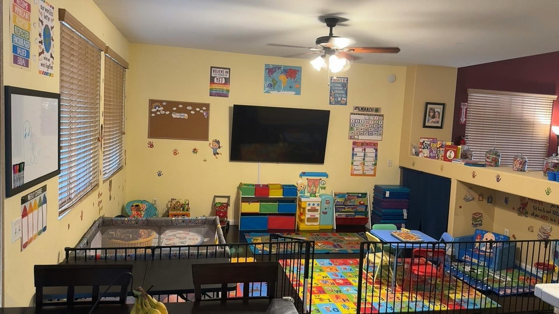 Playroom with colorful mats, playpens, and educational posters on walls