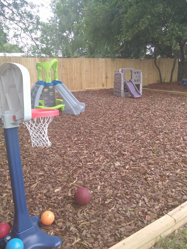 Playground with slides, basketball hoop, and balls on wood chips