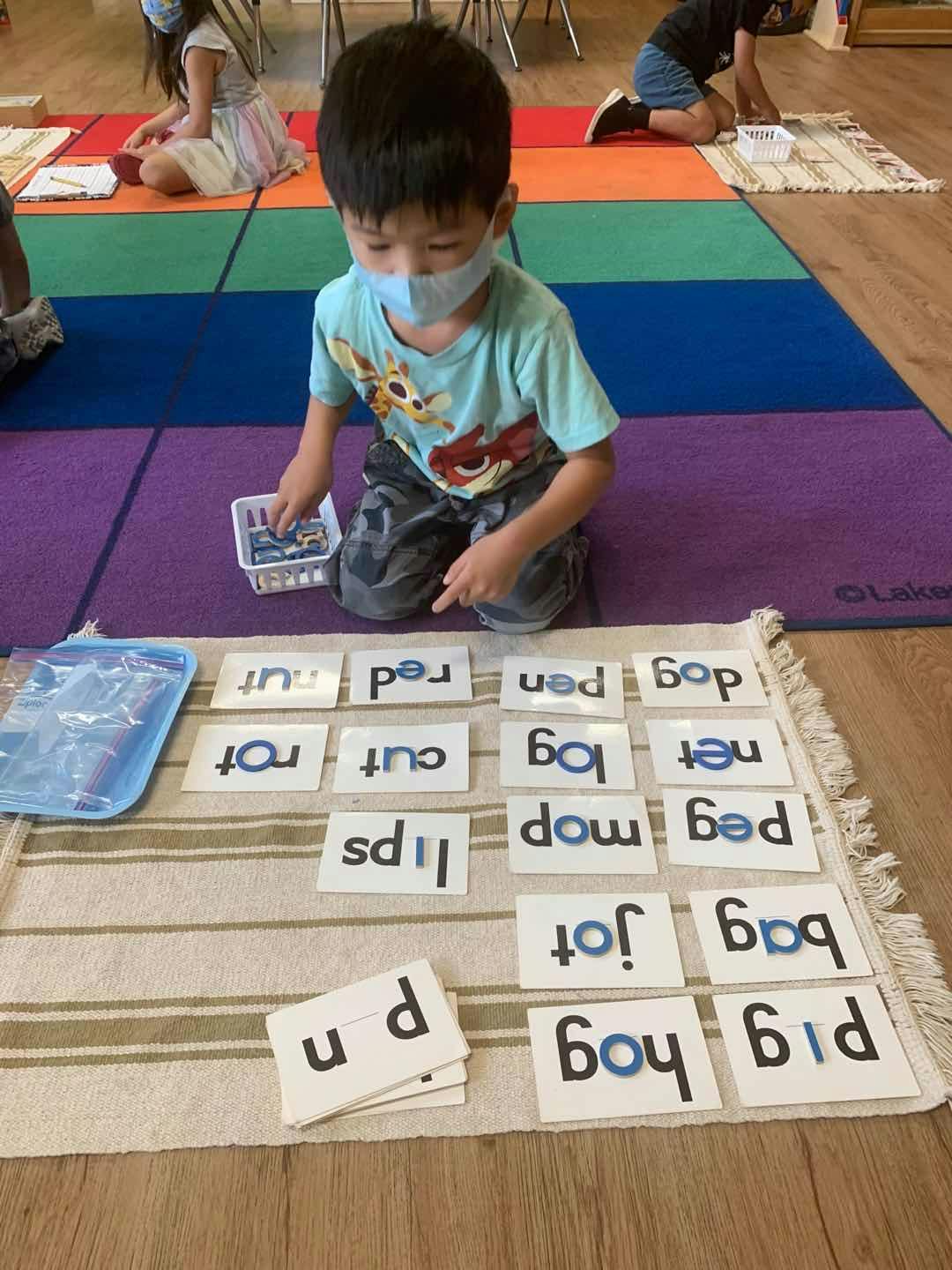 Child in a mask on the floor with word cards