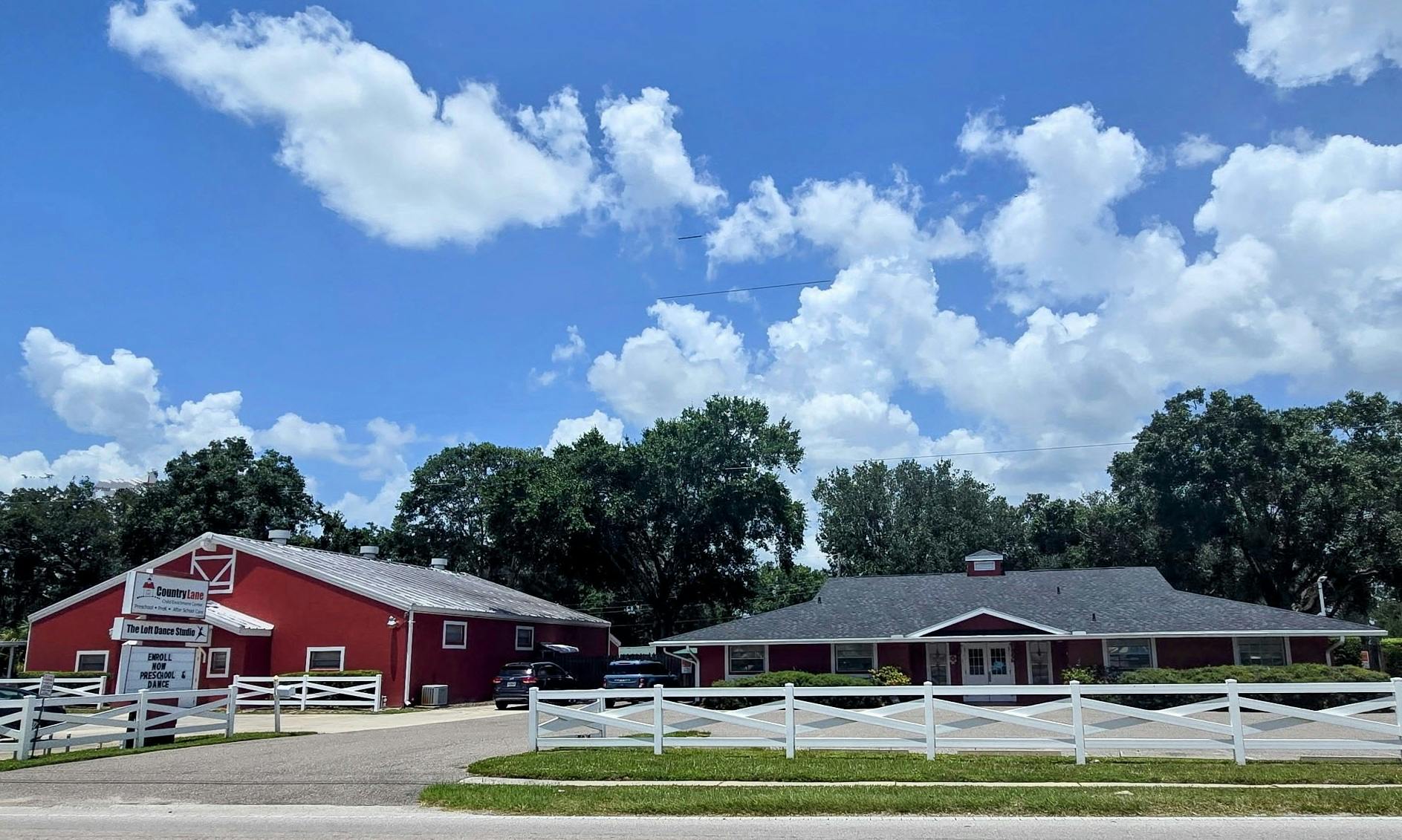 Red barn-style building and a single-story building with a white fence
