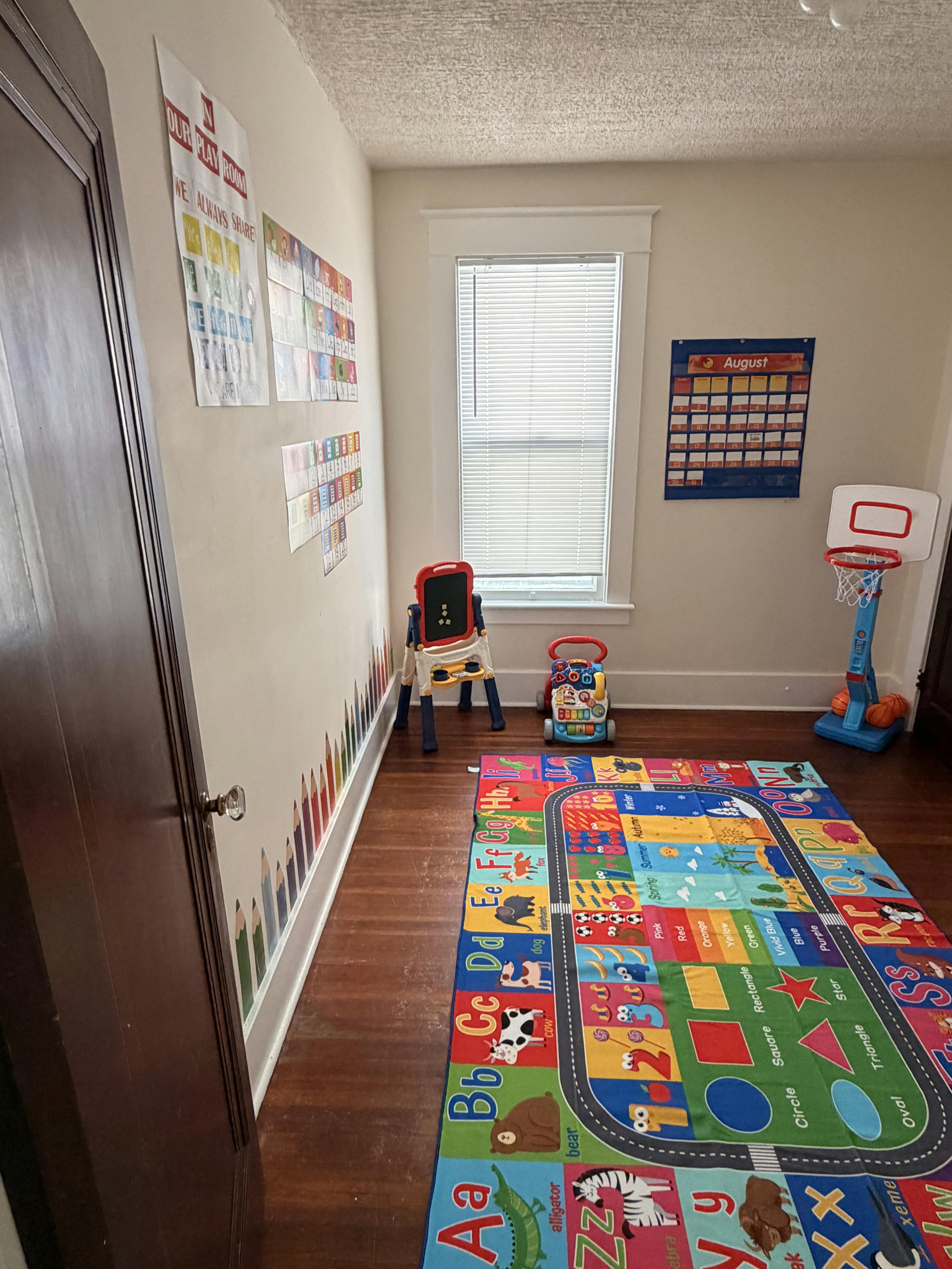 Playroom with educational floor rug, toddler toys, and wall charts
