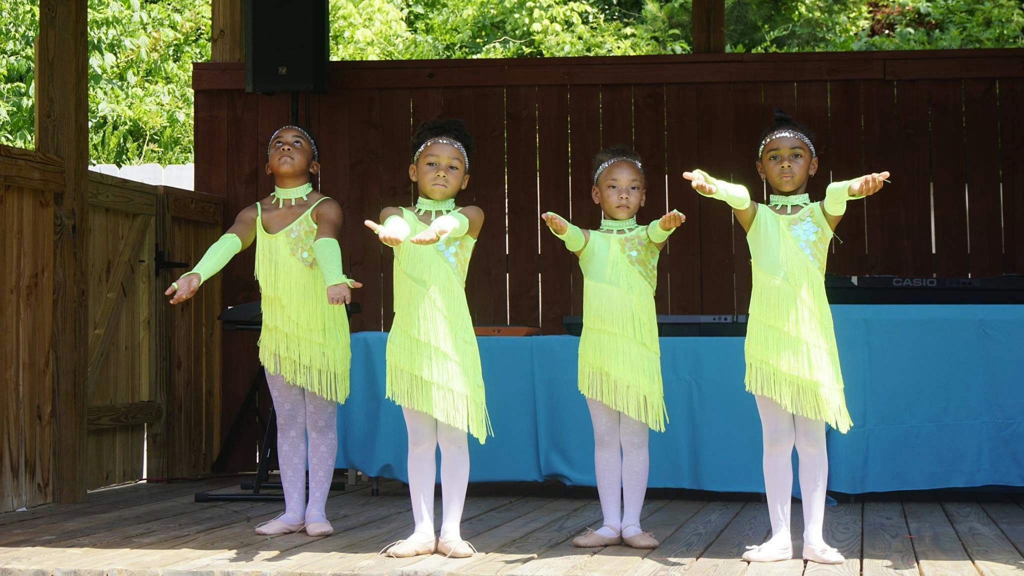 Four children in matching dance costumes performing on a stage