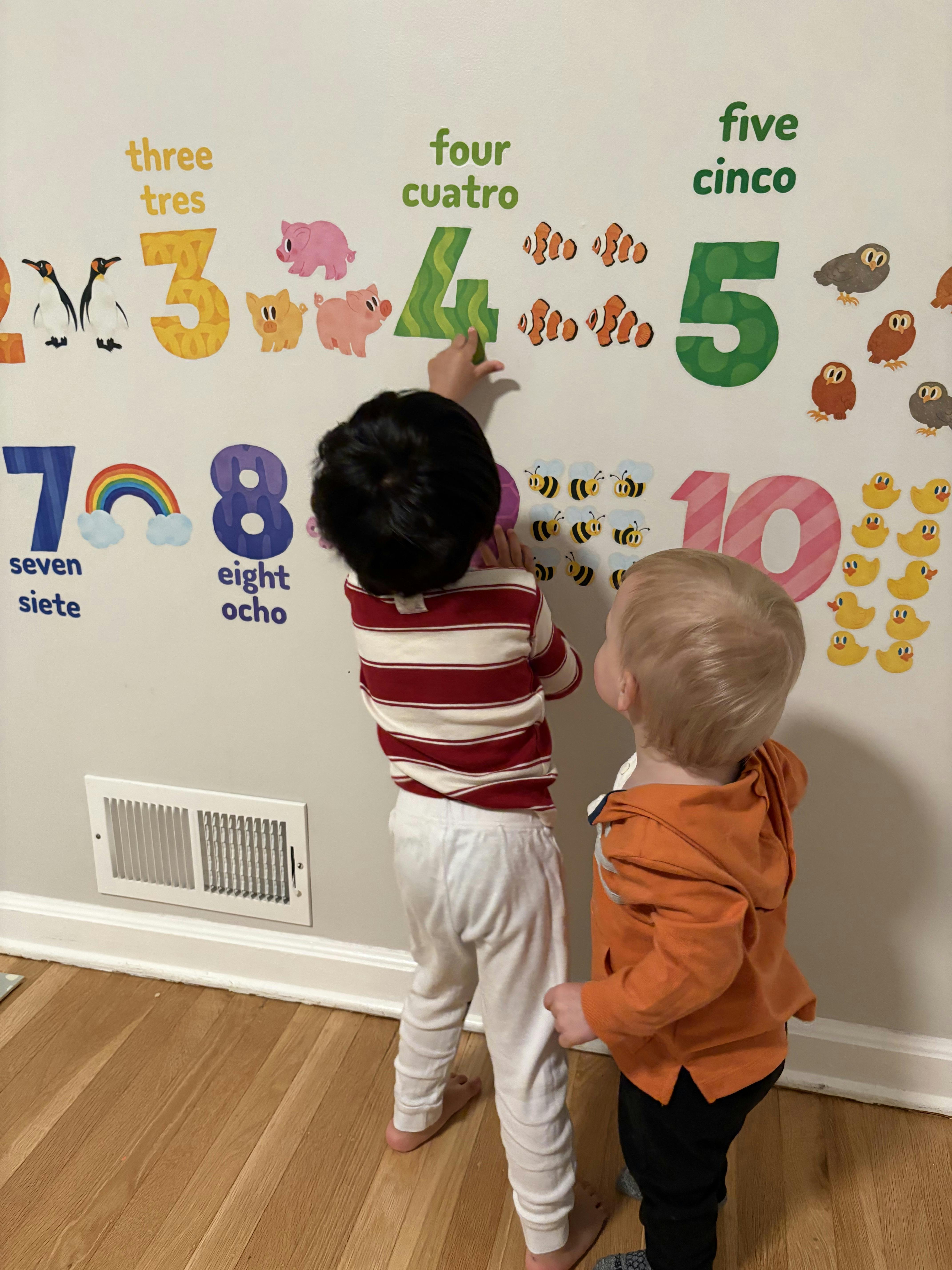 Two young children interacting with number and animal wall decals