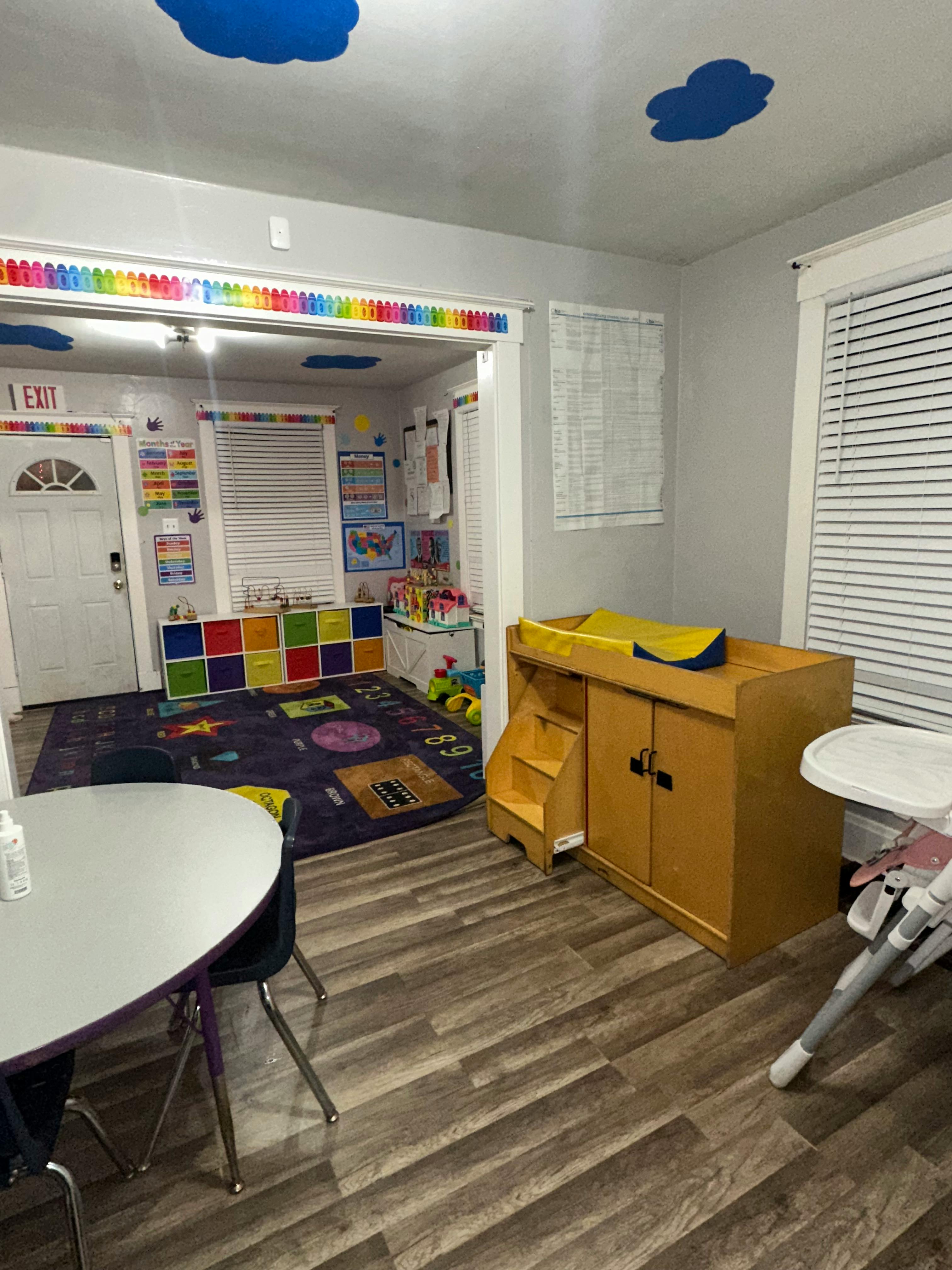 Childcare room with changing table, play rug, and small table