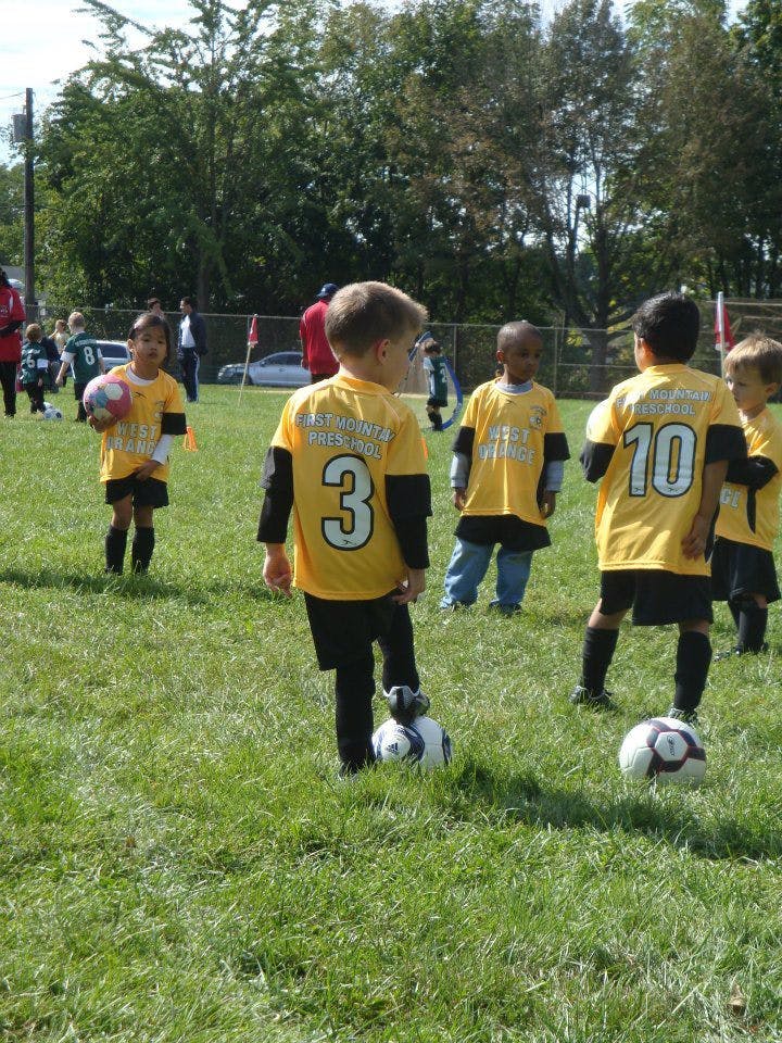 Children in yellow jerseys playing soccer on a grassy field
