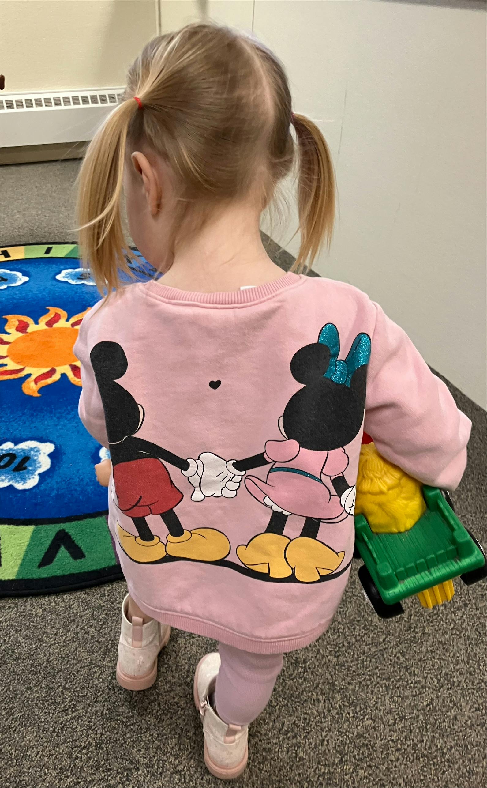 Child with pigtails wearing a shirt with cartoon characters