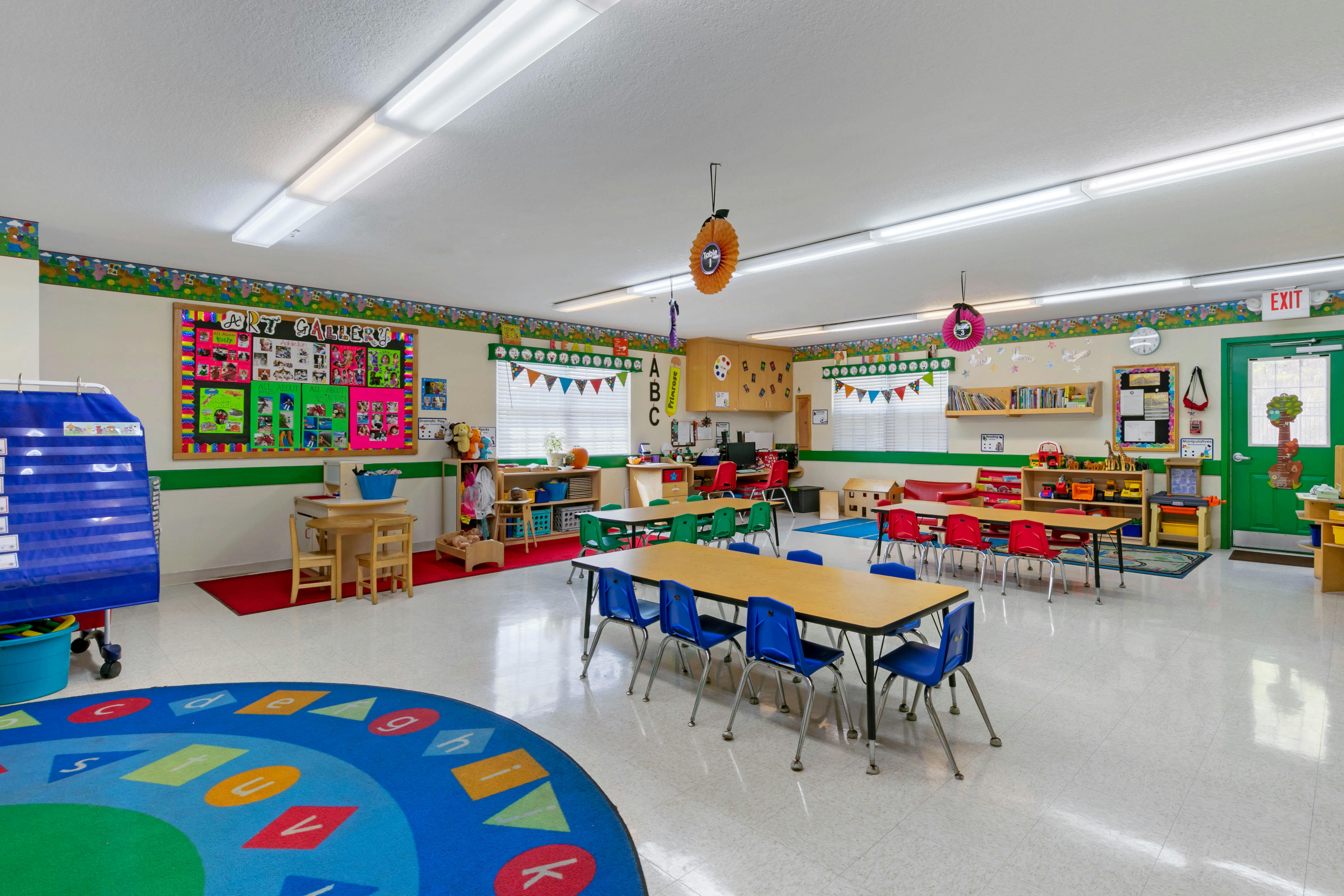 Classroom with child-sized tables and chairs, artwork on walls, and play areas