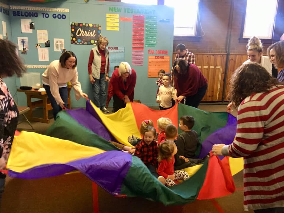 Adults and children playing with a colorful parachute