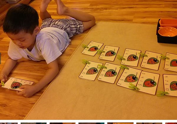 Child lying on floor playing with cards depicting strawberries