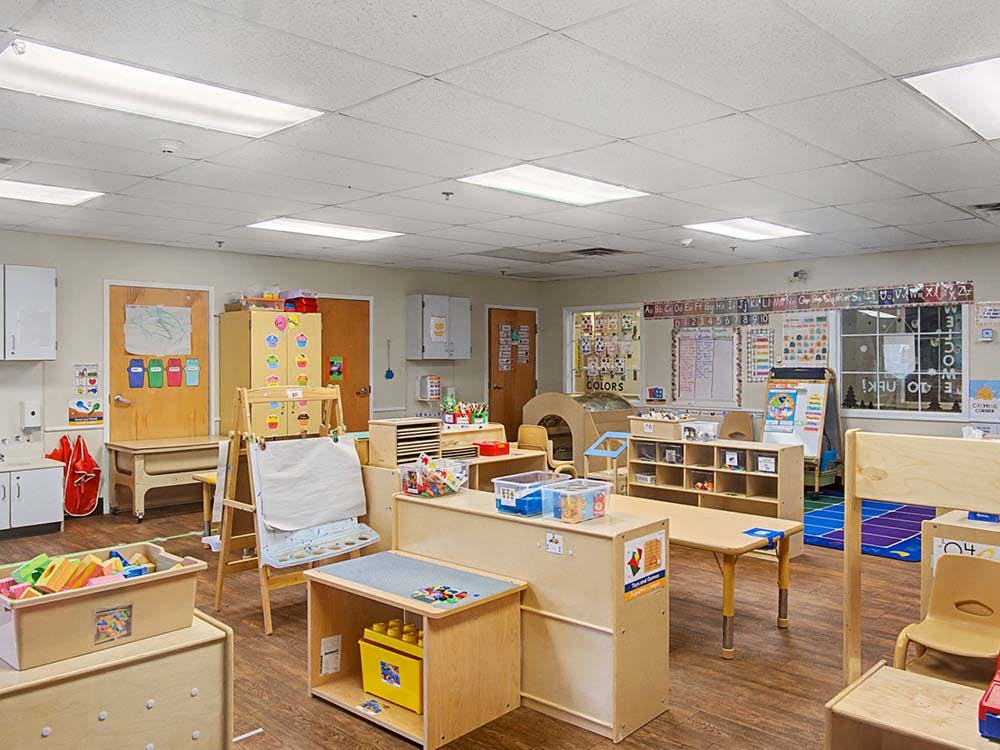 Empty classroom with small tables, chairs, and shelves